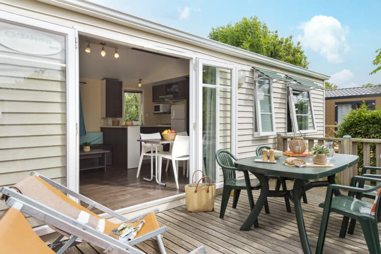 Terrasse mobile home avec intérieur moderne, table et chaises.