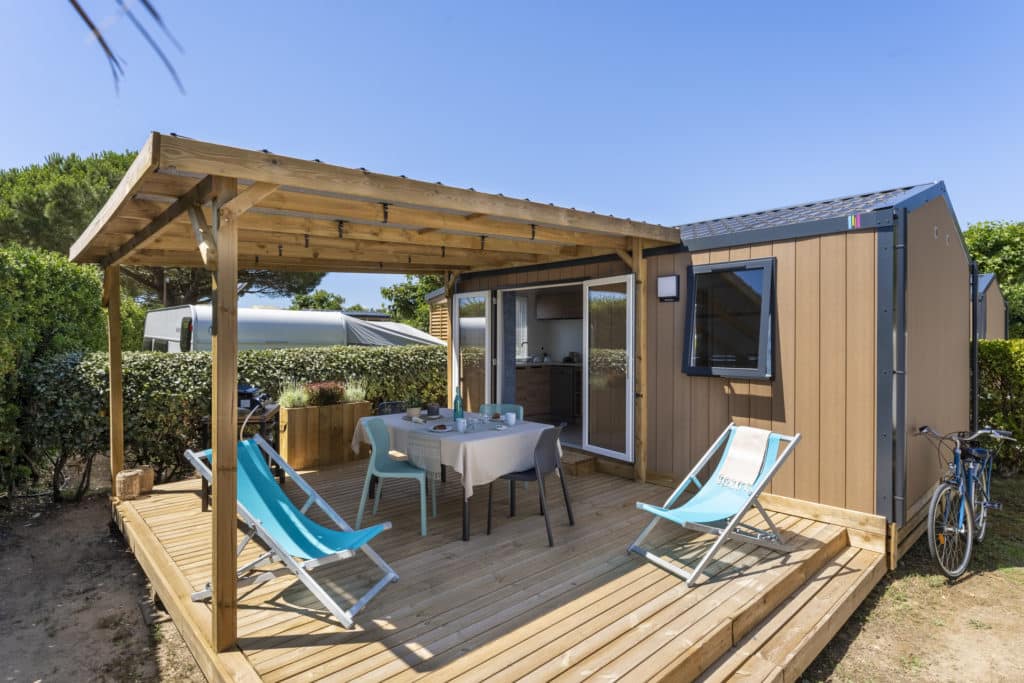 Terrasse en bois avec chaises longues et table.