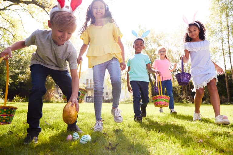 Enfants cherchant des œufs de Pâques dans le jardin.