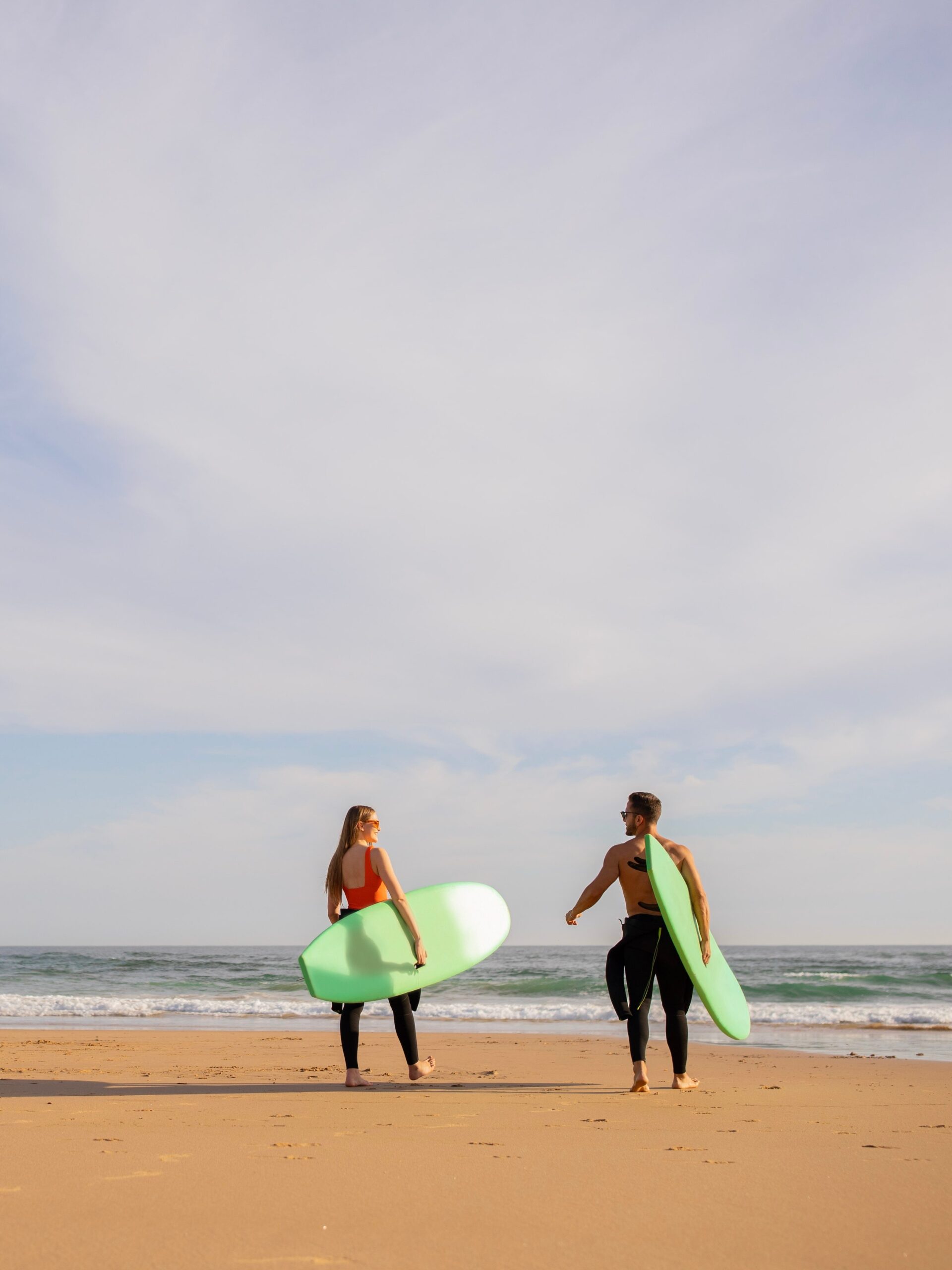 Deux personnes avec des planches de surf qui se dirigent vers l'océan